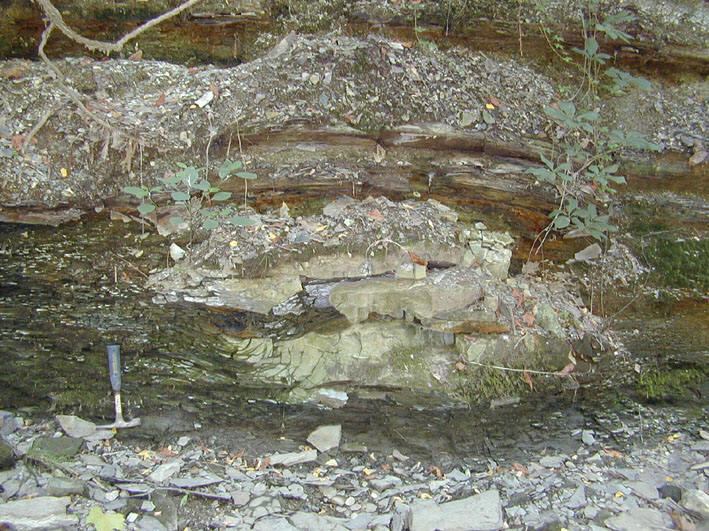A scientific diagram from an IU Shale Research study shows a rock outcrop with a geologic hammer for scale, highlighting a channelized sandstone with a scoured base.